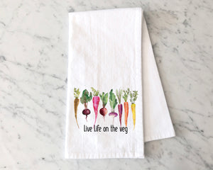 White flour sack towel with colorful root vegetables with the text Live Life on the Veg
